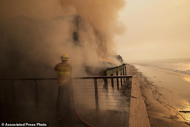 A firefighter protects a beachfront property Thursday while battling the Palisades Fire