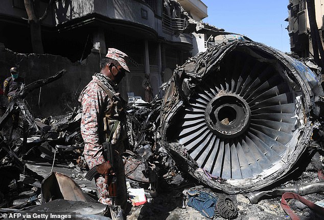 Security personnel stand next to the wreckage of an aircraft at the site after a Pakistan International Airlines plane crashed in a residential area in Karachi on May 24, 2020