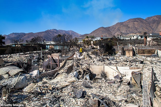 A firefighter inspects a burned home after the Palisades Fire in Los Angeles on Friday