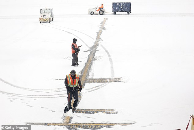 Workers clear snow as it covers Hartsfield-Jackson Atlanta International Airport Friday morning