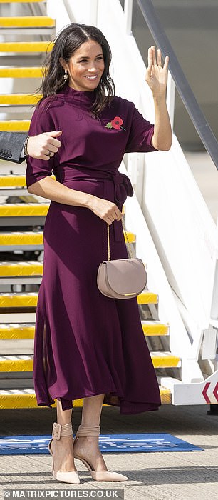 Meghan looked stunning in this burgundy Hugo Boss dress as she boarded the plane to New Zealand