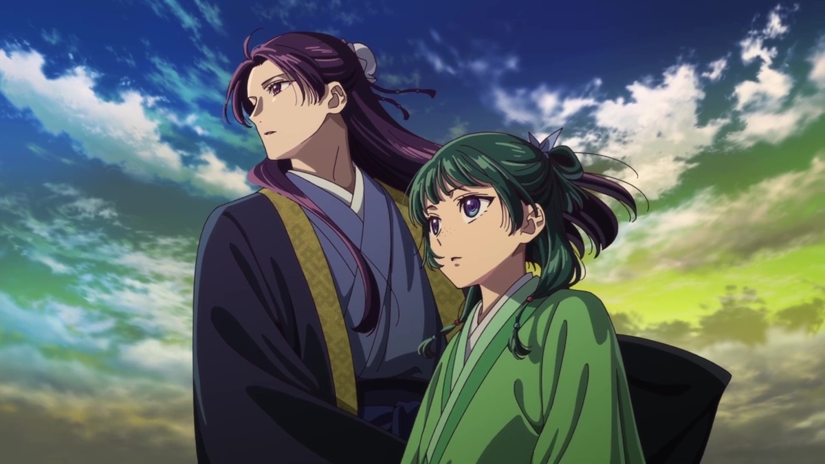 A purple-haired anime man in a dark blue cloak and a green-haired anime woman in a green cloak standing in front of a green and blue sky in The Apothecary Diaries.