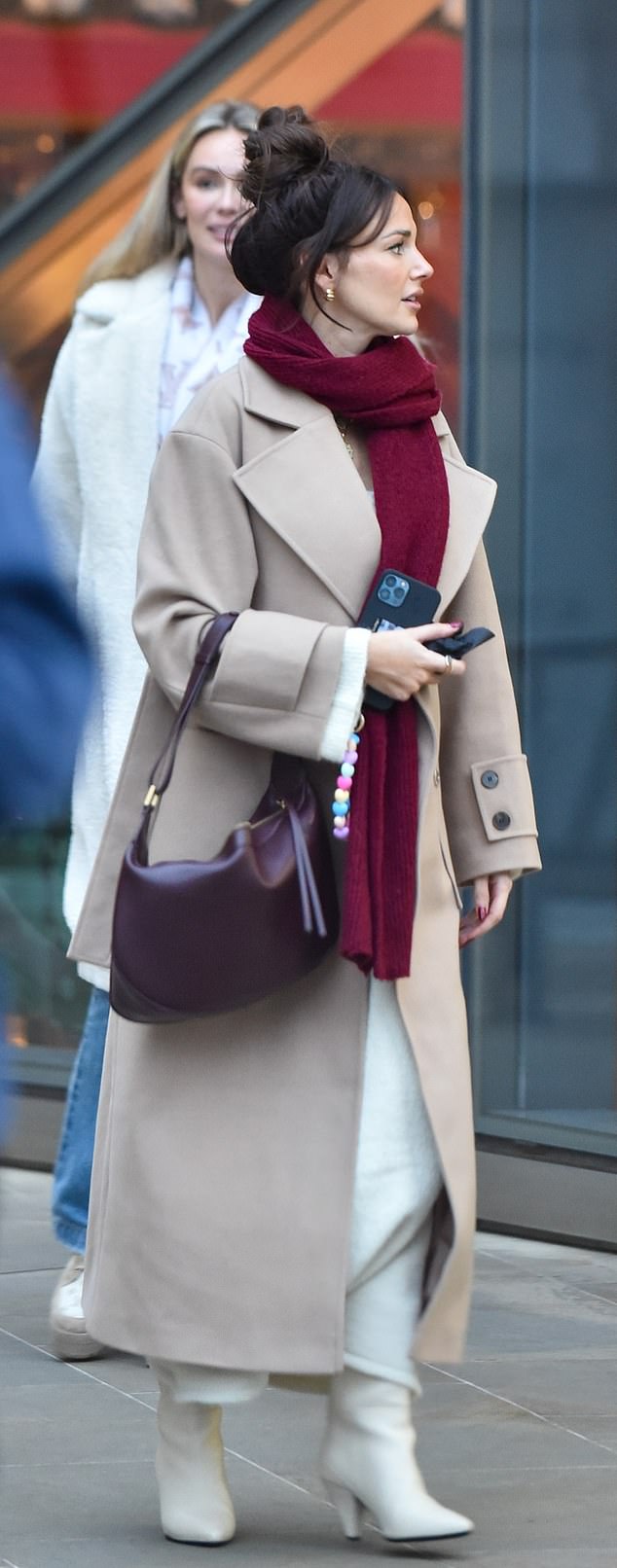 Michelle hid her baby bump last month by wearing a long beige coat and scarf, completing her look with white white boots and a maroon bag