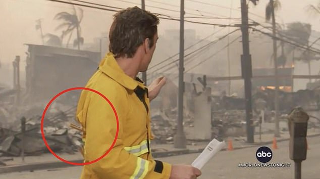 As he turned and pointed to the burned-out remains of a house, clothespins could be seen stuck in the firefighter jacket he was wearing.