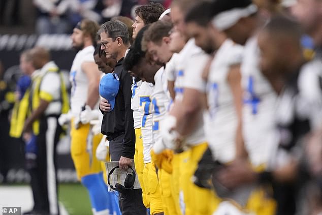 Los Angeles Chargers coach Jim Harbaugh joins players during a moment of silent reflection for California wildfire victims ahead of Saturday's playoff opener in Houston