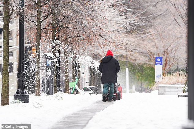 A man uses a snow blower after a snowstorm Friday in Atlanta