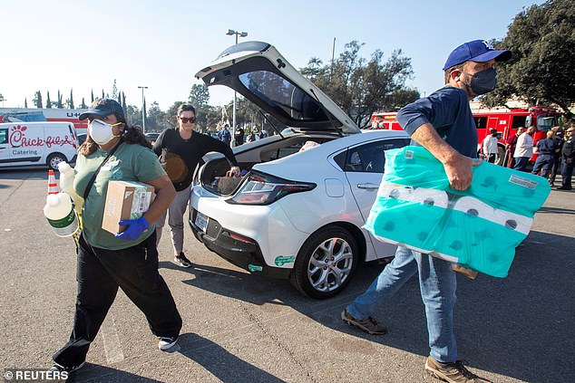 Volunteers unload relief supplies from a car at the YMCA distribution center at Pasadena City College after residents fled the Eaton fire