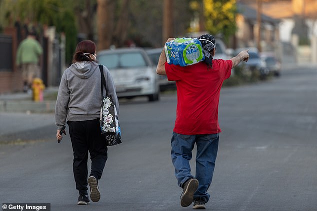 A man carries water in a neighborhood where many homes were destroyed by the Eaton fire