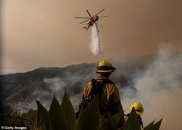 A firefighting helicopter drops water on the Palisades Fire on January 10, 2025