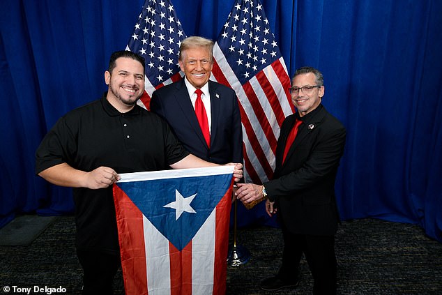 Delgado and his father, who grew up between New York City and Puerto Rico, pose with a Puerto Rican flag after Democrats criticized Trump for featuring a comedian at a rally calling the U.S. territory 