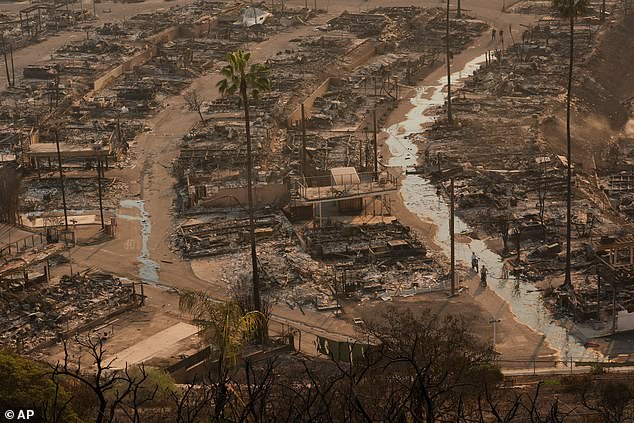 Two people ride bicycles amid the destruction left by the Palisades Fire in the Pacific Palisades neighborhood of Los Angeles, January 9, 2025