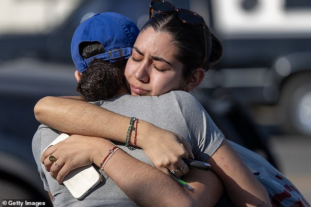 People hug each other in a neighborhood where many homes were destroyed by the Eaton Fire on January 11, 2025 in Altadena, California