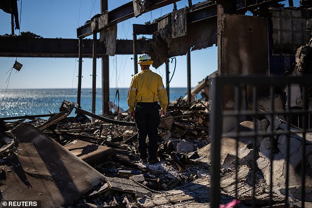 A firefighter inspects a building destroyed by the Palisades Fire in Malibu