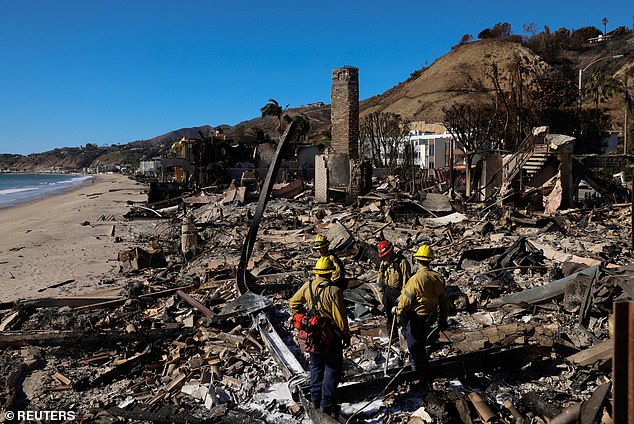 Firefighters search for hot spots in a house that burned down as a result of the Palisades Fire, along the Pacific Coast Highway