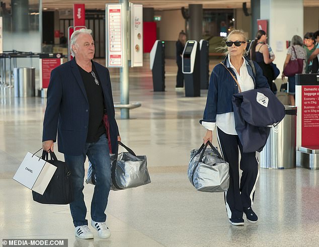 He completed his look with a pair of white Adidas sneakers while also carrying a handful of luggage through the airport