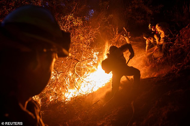 Firefighters extinguish a blaze during the Palisades Fire, one of several simultaneous blazes that have torn through Los Angeles County