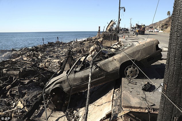 A burned vehicle rests on a destroyed structure during the aftermath of the Palisades Fire