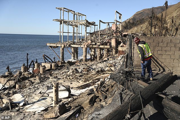 A SoCal Gas employee looks at the destruction in the aftermath of the Palisades Fire along Malibu's Pacific Coast Highway