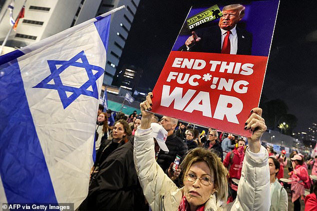 A protester holds a sign calling on newly-elected US President Donald Trump to intervene during an anti-government protest calling for action to secure the release of Israelis held hostage in Gaza since October 2023.