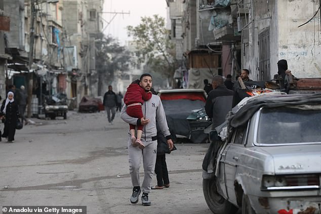 Palestinians leave the area after the Israeli army launched an attack on two buildings in the Bureij camp, located in the central Gaza Strip, on Monday