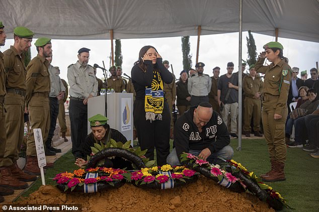 Gali and Nir, the parents of Israeli soldier Sergeant Yahav Maayan who died fighting in the Gaza Strip, react next to his grave during his burial at a military cemetery in Modiin