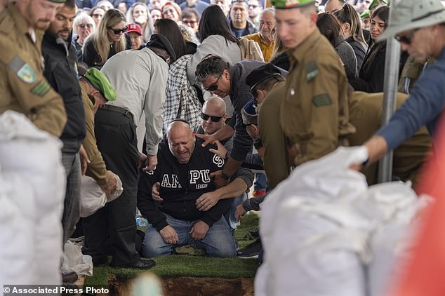 Nir, the father of Israeli soldier Sergeant Yahav Maayan who died in combat in the Gaza Strip, reacts next to his son's grave