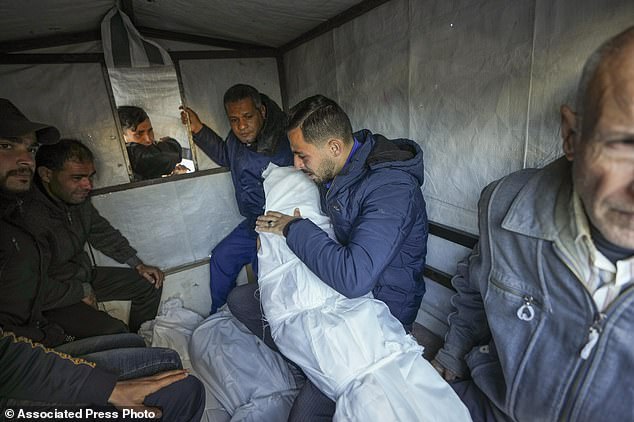 Mohammad Eid carries the body of one of his three relatives killed in an Israeli airstrike on Saturday as they prepare for the funeral in Deir al-Balah, central Gaza Strip on Sunday