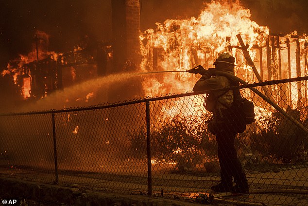 A firefighter sprays water on a burning house in the Eaton Fire in Altadena, California on Wednesday, January 8, 2025