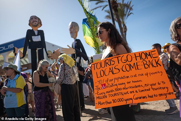 Tenerife locals hold up signs expressing concern about the impact of mass tourism, October 2024