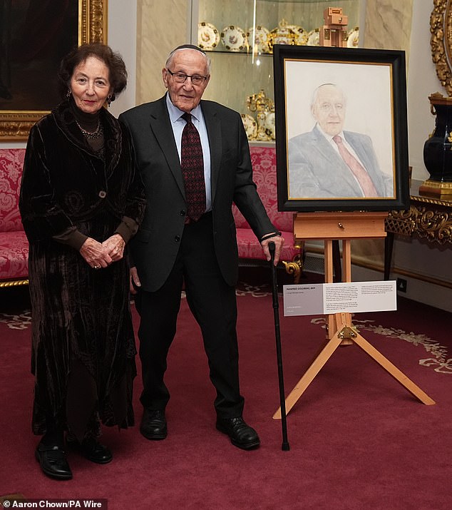 Mr. Goldberg and his wife Shary Goldberg pose next to a portrait of themselves during a reception celebrating Holocaust Memorial Day