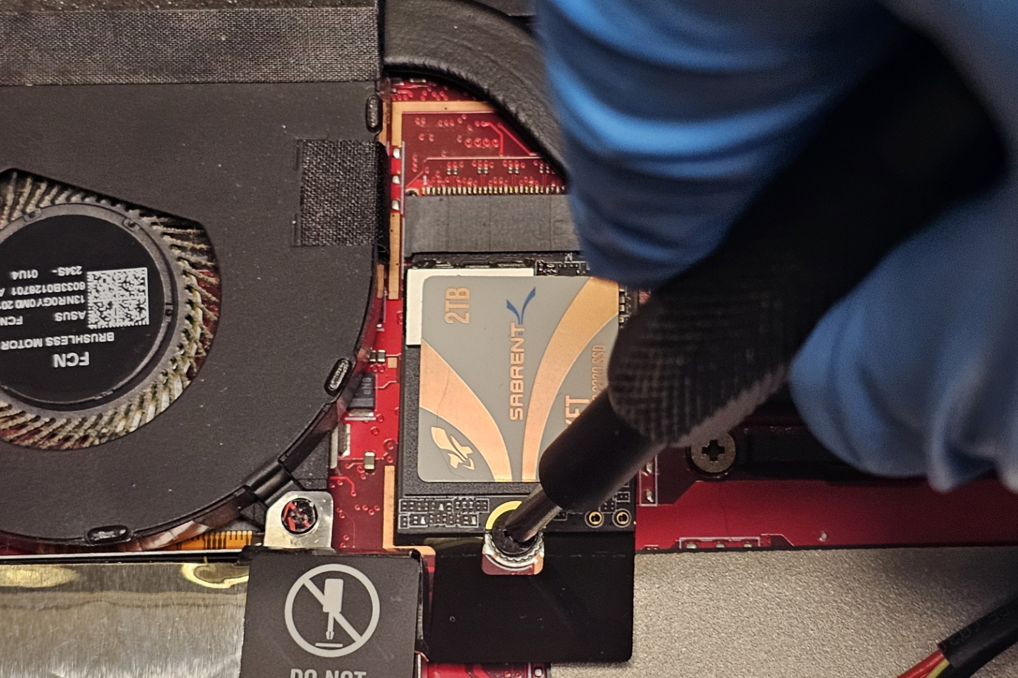 A photo of a hand tightening the screw on an M.2 SSD in ROG Ally