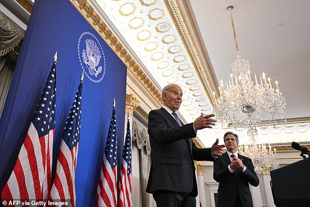 President Joe Biden (left) responds to applause as he is greeted by State Department and other administration officials at the Department of State headquarters in DC, along with Secretary of State Antony Blinken (right)