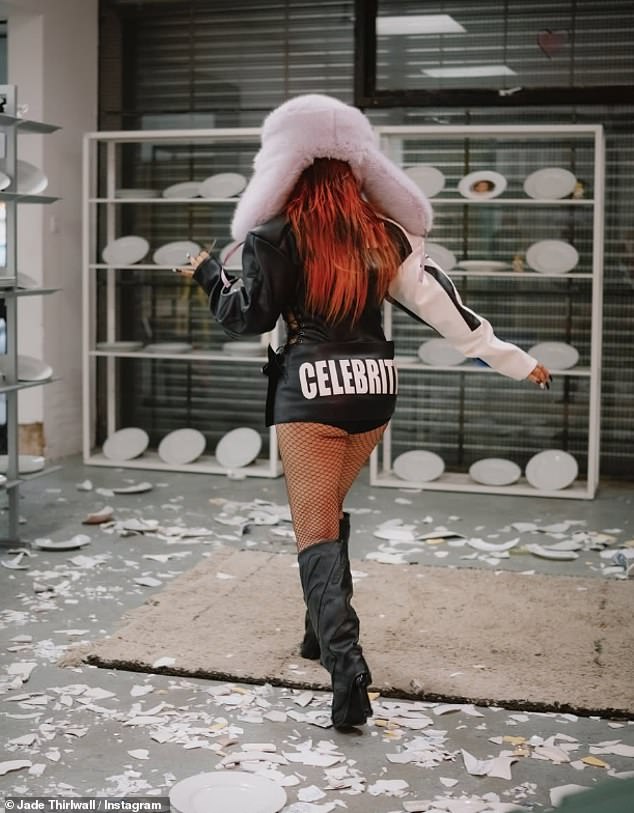 In one shot, the singer struck a moody pose in a pair of fishnets while holding a banner that read "CELEBRITY" and looked sensational in the sports bra and boots combo.