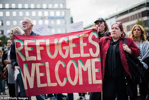 People hold a 'refugees welcome' banner as they take part in a demonstration in solidarity with refugees seeking asylum in Europe after fleeing their homeland in Stockholm on September 12, 2015.