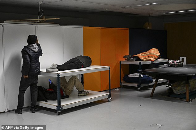 People sleep under a table, on furniture and charge mobile phones during an occupation action in the Gaite Lyrique theater