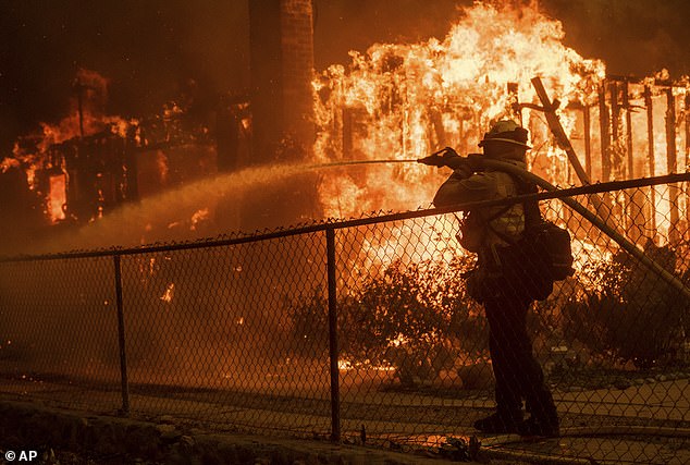 Pictured: A firefighter sprays water on a burning house in the Eaton Fire in Altadena, California on Wednesday, January 8, 2025