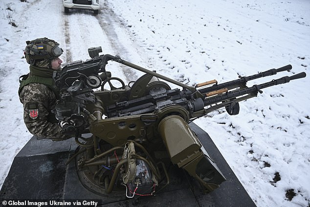 A Ukrainian soldier from the mobile air defense unit sits behind an anti-UAV machine gun