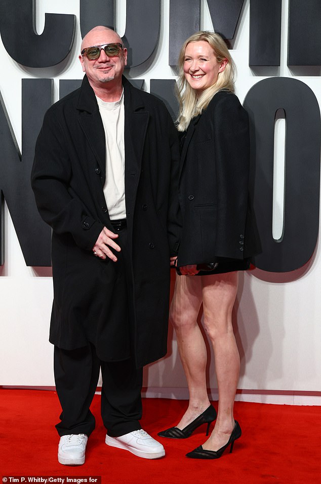 Huey laughed as he walked along the carpet hand-in-hand with his wife, wearing a long black coat