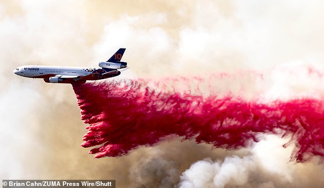 A plane is seen dropping fire retardant into Mandeville Canyon, one of the neighborhoods threatened by the Palisades Fire on Saturday