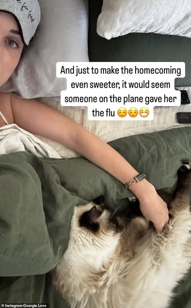 She shared a photo of herself to her Instagram Stories on Wednesday as she lay in bed with the flu and cuddled with her ragdoll cat as she recovered