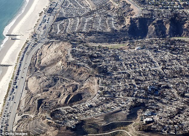 An aerial view of fire trucks, utility vehicles and other vehicles parked along the Pacific Coast Highway near homes destroyed by the Palisades Fire on Monday