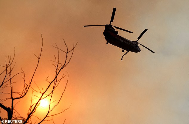 A helicopter flies over the Palisades Fire, one of several simultaneous fires that have torn through Los Angeles County