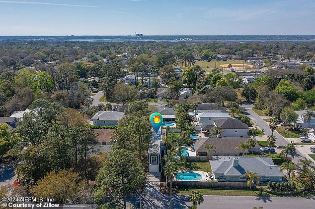 The narrow building, surrounded by a white picket fence, is no less than 40 meters high and looms over the surrounding family homes, swimming pools and backyards.