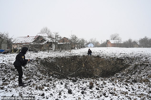 Members of the Ukrainian police investigate a crater after an attack on the village of Sknyliv, some 60 kilometers from Lviv, on January 15