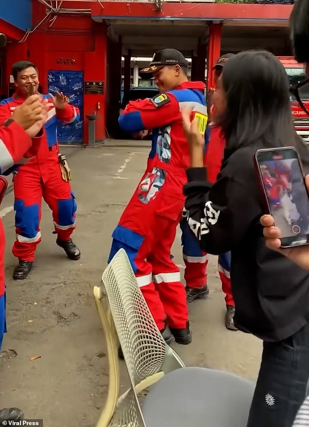 The woman excitedly stood up from the chair after finally being freed, while the firefighters celebrated with a dance