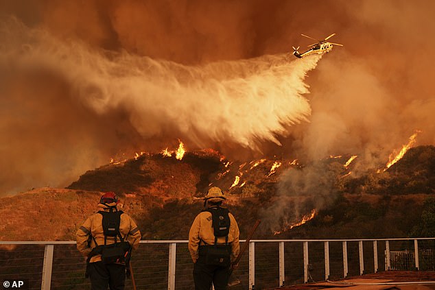 Firefighters watch as water is dropped on the Palisades Fire in Mandeville Canyon on Saturday, January 11, 2025