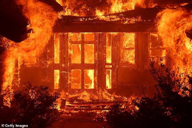 Flames from the Eaton Fire in Altadena engulf a home as the massive blaze sweeps through the area