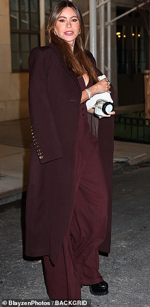 She fashionably threw a wine-colored coat over her shoulders and added a touch of contrast to the look with a white Yves Saint Laurent clutch