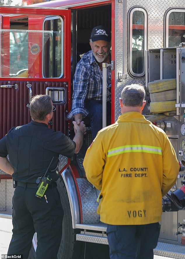 The actor is seen shaking hands with firefighters who took him on a tour of the once luxurious neighborhood