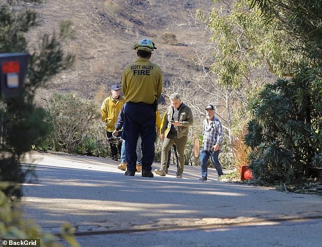 Mel Gibson walks with firefighters through his Malibu neighborhood on Wednesday